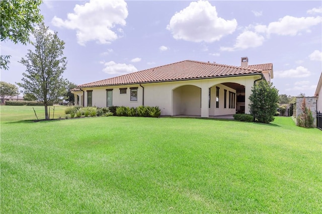 4231 Villaggio Ct, Bryan, TX 77802 - back of property featuring a tiled roof, a chimney, a lawn, and stucco siding