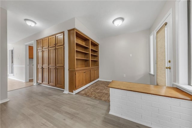 unfurnished dining area featuring baseboards and light wood-type flooring
