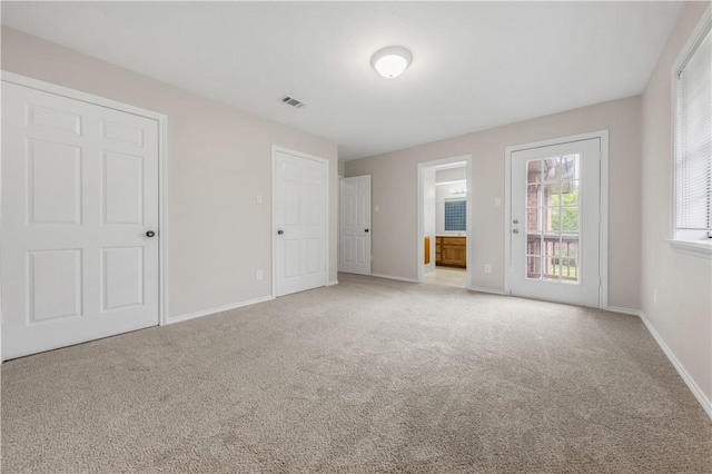 unfurnished bedroom with connected bathroom, baseboards, visible vents, and carpet