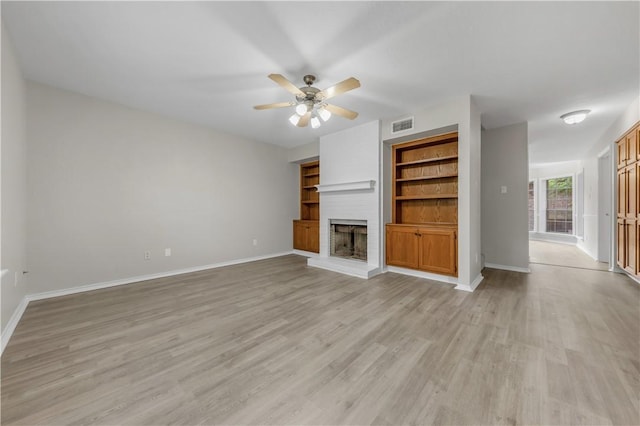 unfurnished living room with visible vents, a fireplace, baseboards, ceiling fan, and light wood-type flooring