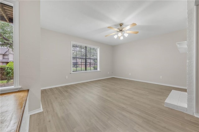 unfurnished living room featuring light wood-type flooring, a ceiling fan, and baseboards