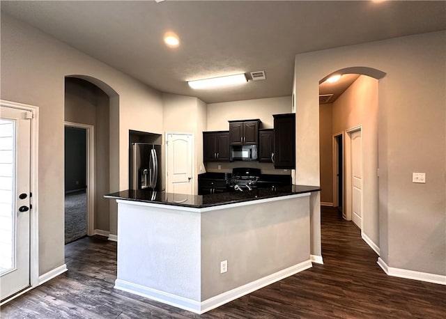 kitchen with arched walkways, black microwave, stainless steel refrigerator with ice dispenser, and gas range oven