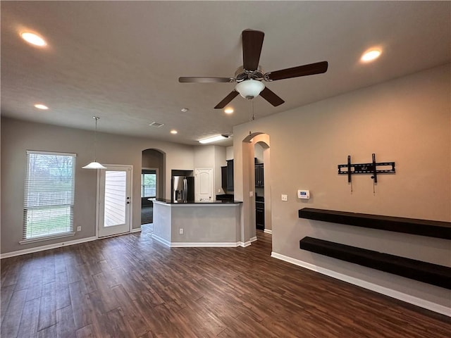 interior space featuring arched walkways, dark wood-style floors, and baseboards