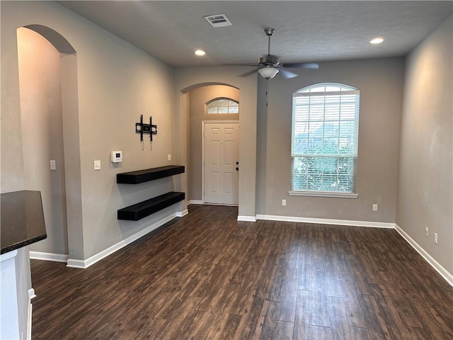 foyer with arched walkways, dark wood finished floors, visible vents, and baseboards