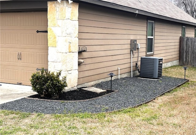 view of home's exterior with a garage, a shingled roof, cooling unit, and fence