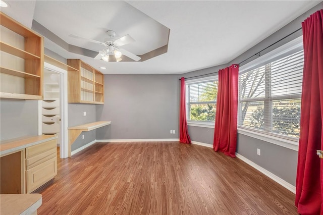 interior space featuring ceiling fan, built in desk, and hardwood / wood-style floors