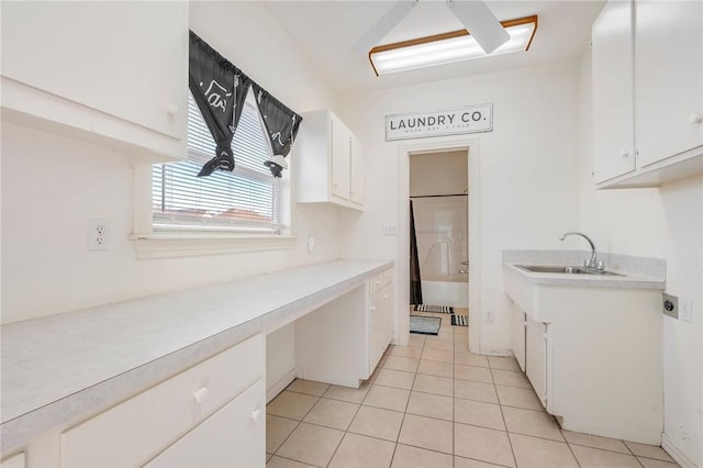 kitchen with sink, light tile patterned floors, and white cabinets