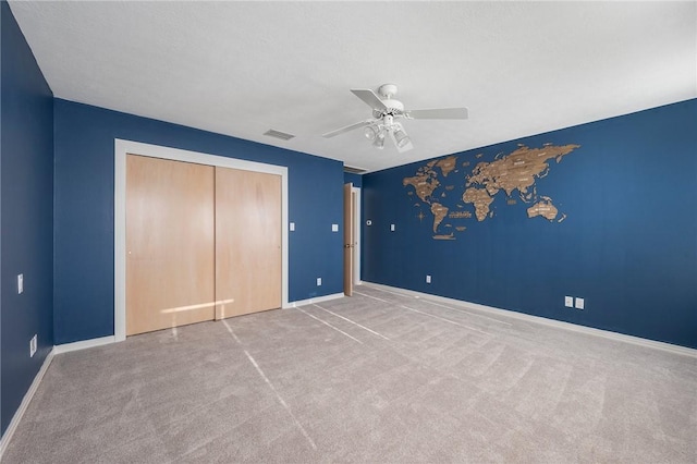 unfurnished bedroom featuring light colored carpet, ceiling fan, and a closet