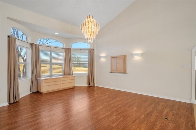 unfurnished room with wood-type flooring, vaulted ceiling, and a chandelier