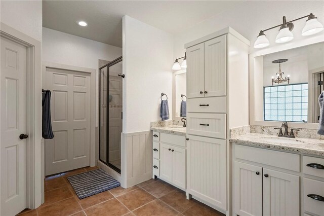 full bathroom featuring tile patterned floors, a sink, a shower stall, and a chandelier