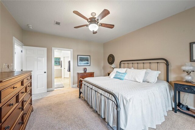 bedroom featuring connected bathroom, light colored carpet, baseboards, visible vents, and a ceiling fan