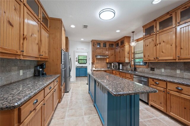 kitchen with tasteful backsplash, a healthy amount of sunlight, stainless steel appliances, and a kitchen island