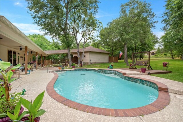 outdoor pool featuring fence, a ceiling fan, a yard, and a patio area
