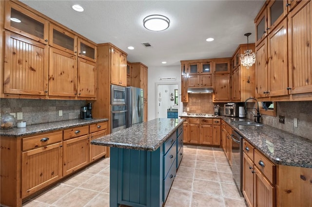 kitchen with decorative backsplash, stainless steel appliances, under cabinet range hood, brown cabinets, and a sink