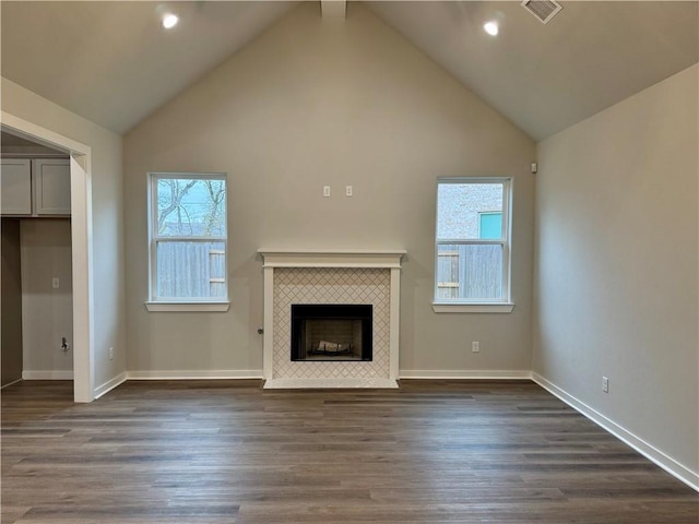 unfurnished living room featuring a tile fireplace, lofted ceiling, and dark hardwood / wood-style floors