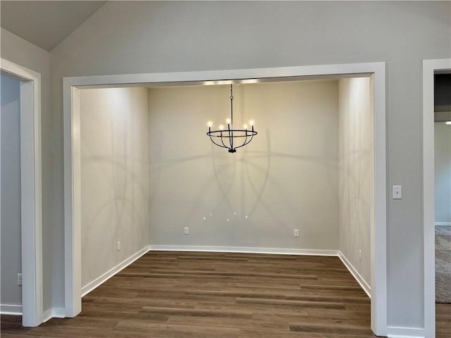 unfurnished dining area with a notable chandelier, dark wood-type flooring, and vaulted ceiling