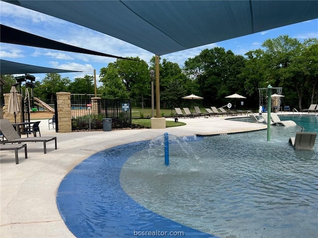 view of pool with a playground, pool water feature, and a patio