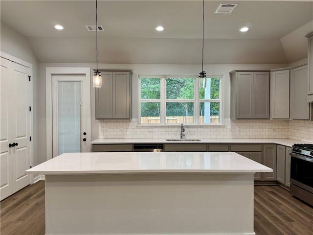 kitchen with stainless steel gas range oven, sink, pendant lighting, and lofted ceiling