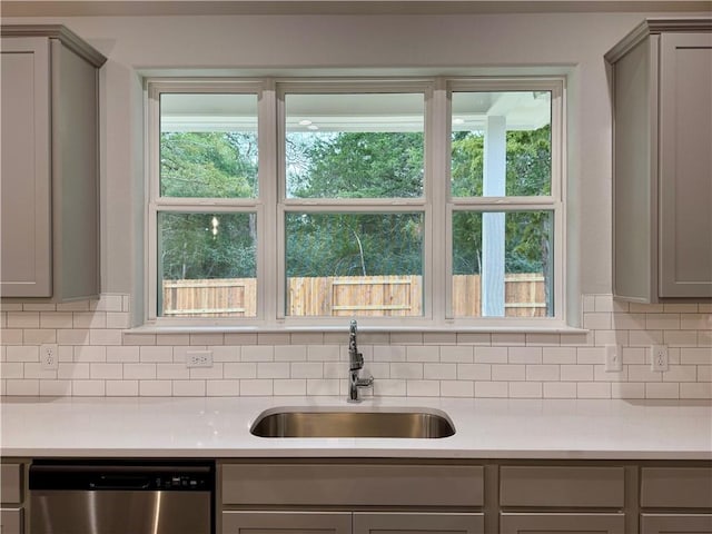 kitchen with dishwasher, sink, decorative backsplash, gray cabinets, and a wealth of natural light