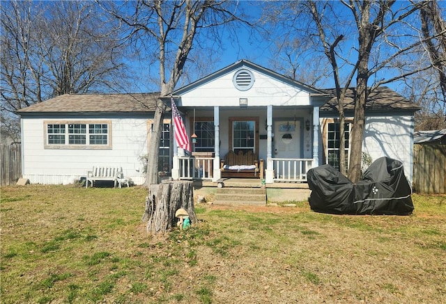 view of front of house with covered porch, a front lawn, and fence