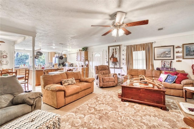 living room featuring ceiling fan, crown molding, and a textured ceiling