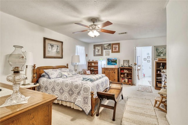 carpeted bedroom featuring ceiling fan and a textured ceiling