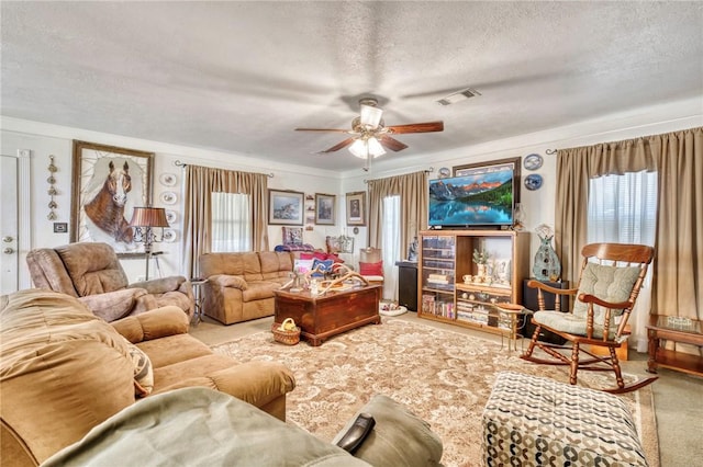 carpeted living room featuring ceiling fan, plenty of natural light, crown molding, and a textured ceiling