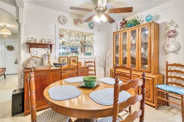 tiled dining space with ornate columns, ceiling fan, and ornamental molding