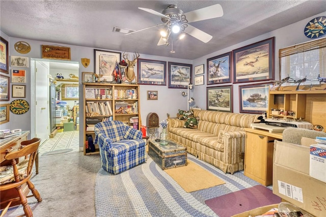 sitting room with ceiling fan, carpet floors, and a textured ceiling