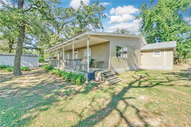 rear view of property featuring a lawn and an outdoor structure