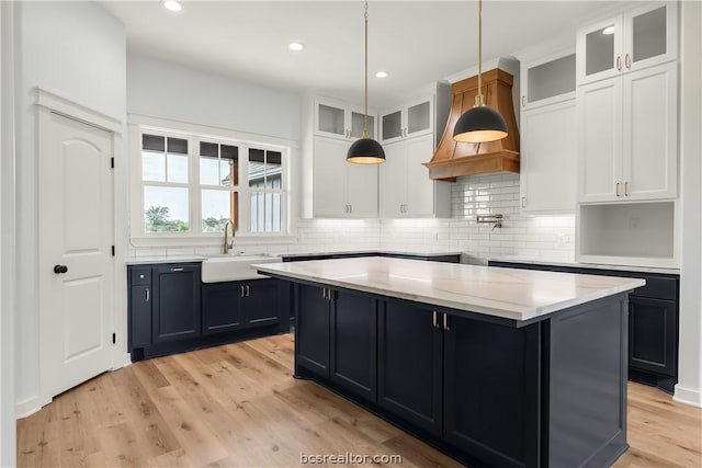 kitchen featuring white cabinetry, sink, a center island, and light wood-type flooring