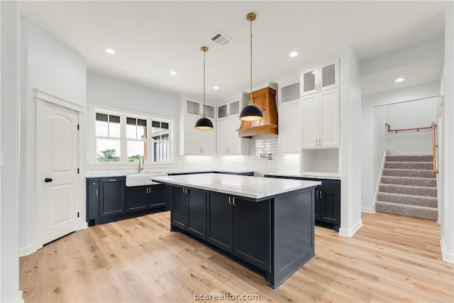 kitchen with white cabinets, a kitchen island, light hardwood / wood-style floors, and sink