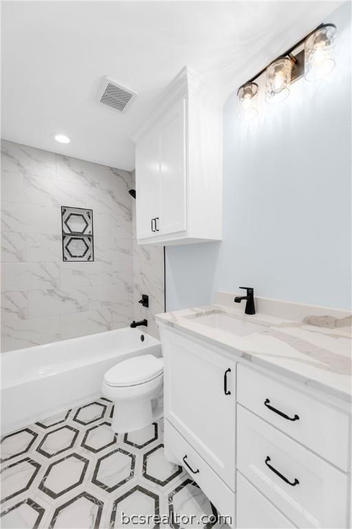 full bathroom with vanity, tiled shower / bath combo, and toilet