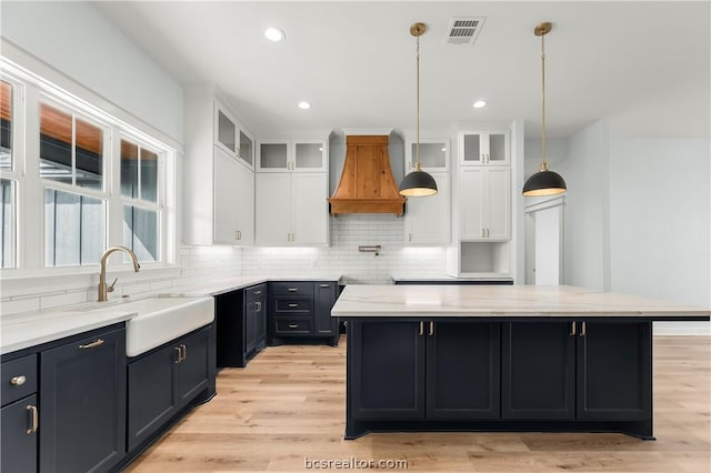 kitchen with premium range hood, a center island, and white cabinets