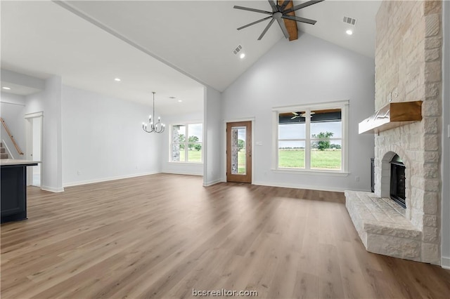 unfurnished living room with high vaulted ceiling, light hardwood / wood-style floors, a stone fireplace, and plenty of natural light