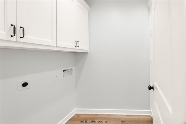 clothes washing area with hookup for an electric dryer, light hardwood / wood-style floors, cabinets, and washer hookup