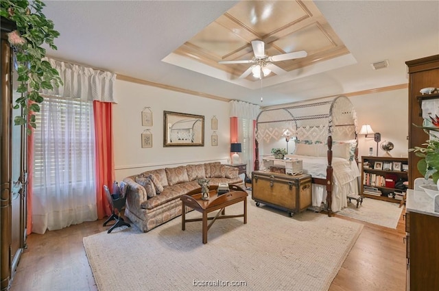 bedroom with hardwood / wood-style floors, a raised ceiling, ceiling fan, and crown molding