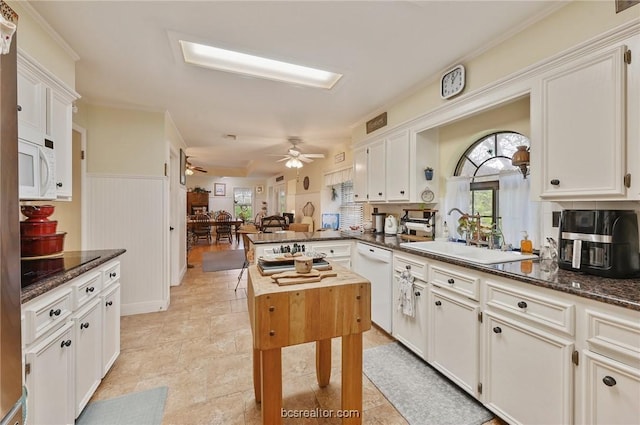 kitchen featuring kitchen peninsula, white appliances, white cabinets, and dark stone countertops