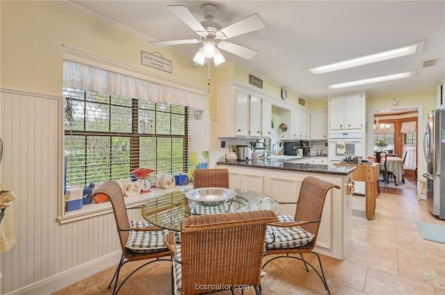 dining space featuring crown molding, ceiling fan, a healthy amount of sunlight, and sink