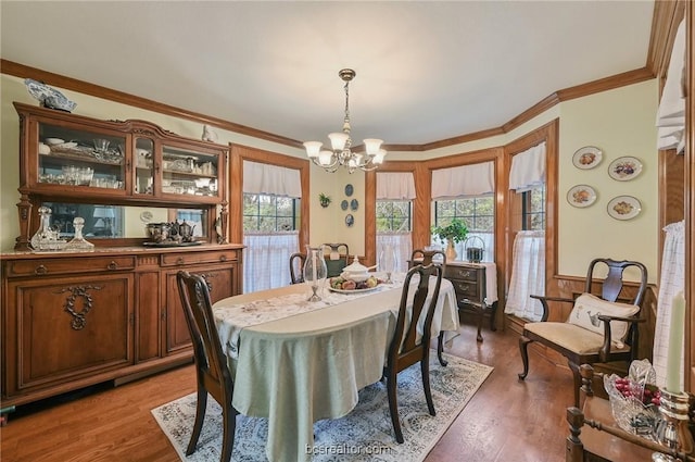 dining area with wood-type flooring, an inviting chandelier, and crown molding