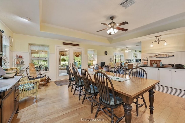 dining room with a tray ceiling, ceiling fan, french doors, and light hardwood / wood-style floors