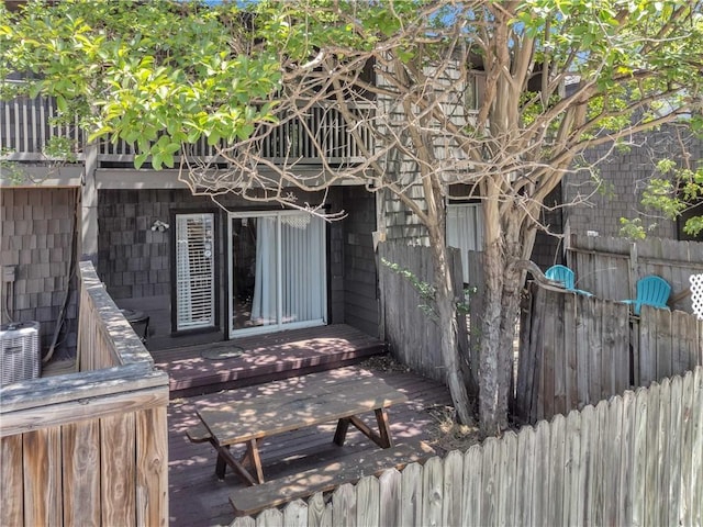 exterior space with central AC unit, fence, and a wooden deck