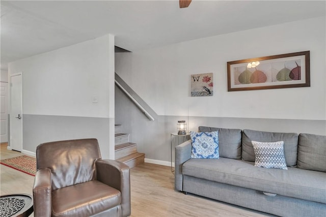 living room featuring baseboards, wood finished floors, and stairs
