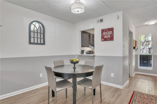 dining room featuring light wood finished floors, baseboards, and visible vents
