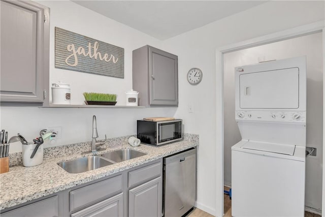 laundry room with stacked washer and clothes dryer, light wood-style floors, and a sink
