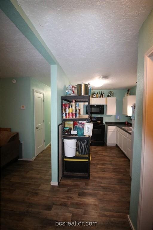 kitchen featuring black appliances, dark hardwood / wood-style floors, white cabinetry, and a textured ceiling