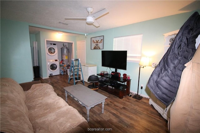 living room featuring ceiling fan, gas water heater, stacked washing maching and dryer, and dark wood-type flooring