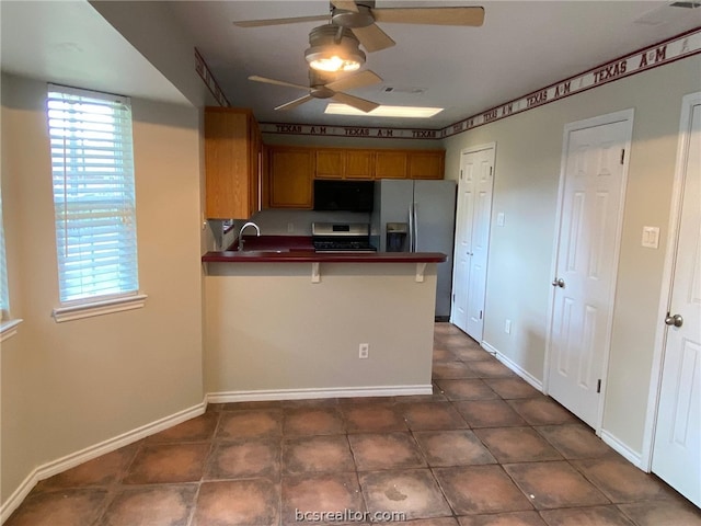 kitchen with kitchen peninsula, a breakfast bar, stainless steel appliances, and dark tile patterned flooring