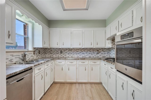 1905 Nueces Dr, College Station, TX 77840 - kitchen featuring appliances with stainless steel finishes, white cabinetry, light wood finished floors, and tasteful backsplash
