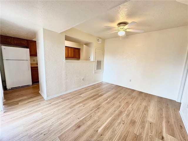 unfurnished living room featuring ceiling fan, light hardwood / wood-style floors, and a textured ceiling